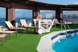 a pool on the top of a building with chairs and a pool table at AC Hotel Gran Canaria by Marriott in Las Palmas de Gran Canaria
