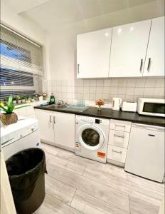 a white kitchen with a washing machine in it at 2 bed flat near to Tower Bridge in London +5 photos
