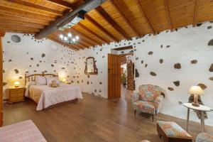 1 dormitorio con 1 cama y pared de piedra en Casa Las Toscas, en Ingenio