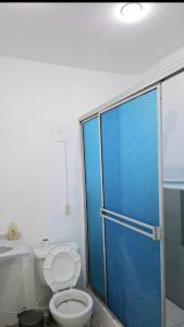 a bathroom with a toilet and a blue shower door at Casa Martín in Bogotá