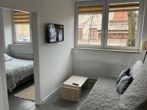 a bedroom with a bed and a table and two windows at City Center Szczytno in Szczytno