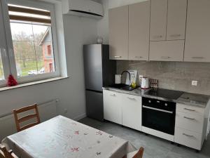 a kitchen with white cabinets and a table and a window at City Center Szczytno in Szczytno