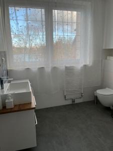 a bathroom with a sink and a toilet and a window at City Center Szczytno in Szczytno