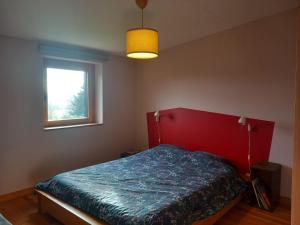 a bedroom with a bed with a red headboard and a window at Maison en bois à la campagne proche vilaine in Férel