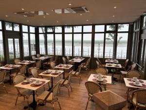 a restaurant with tables and chairs and windows at Logis Hôtel- Restaurant Le Relais Guillaume de Normandy-PARKING GRATUIT--VUE BAIE TERRASSE-CALME-BORNES ELECTRIQUE-LOCAL VELOS SÉCURISÉ in Saint-Valéry-sur-Somme