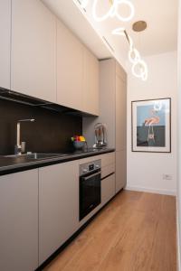 a kitchen with white cabinets and a sink at Alfiere Arc Loft by Klodge in Olbia