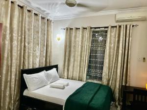 a bedroom with a bed and a window with curtains at Casazuri Homestay in Dar es Salaam