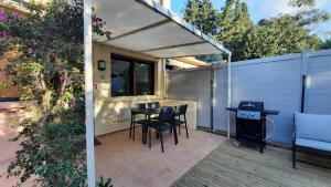 a patio with a table and chairs and a fence at Studio climatisé Lantanas 4 personnes in Le Lavandou