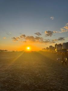 Apartamento vista mar 72 في برايا جراندي: غروب الشمس على شاطئ مع مدينة في الخلفية +34 صورة