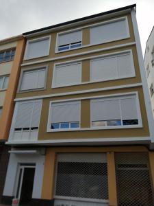 a building with white roller blinds on it at Apartamento Salgueiro ORTIGUEIRA in Santa Marta de Ortigueira