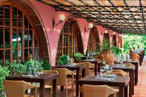 restauracja ze stołami i krzesłami oraz różową ścianą w obiekcie Renaissance Tuscany Il Ciocco Resort & Spa w mieście Barga