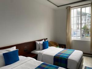 a hotel room with two beds and a window at Villa Cassandra in Nuwara Eliya +42 photos