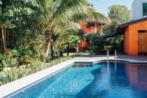 a swimming pool next to a house with a palm tree at Unelma Bungalows in Bucerías
