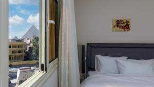 une chambre avec un lit et une fenêtre avec vue dans l'établissement Pyramids Art View Inn, au Caire