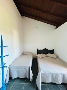 two beds sitting next to each other in a room at Casa pé na areia praia Garopaba in Garopaba +6 photos