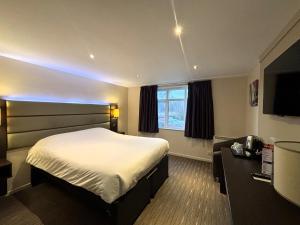 a hotel room with a bed and a television at Premier Roomz Two Mills in Ledsham