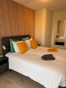 een slaapkamer met een groot bed met oranje en groene kussens bij Appartement Belle Mer - Adults Only in Middelkerke