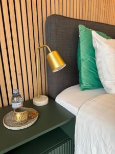 een bed met een tafel met een fles water en een lamp bij Appartement Belle Mer - Adults Only in Middelkerke