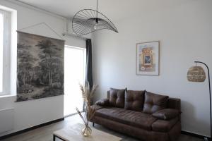 a living room with a brown couch and a window at Maison COSY et CHALEUREUSE au centre ville in Mont-de-Marsan