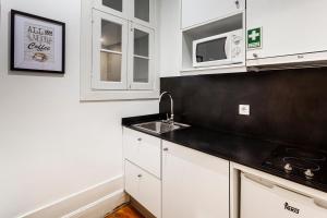 a kitchen with white cabinets and a sink and a microwave at Citybreak-apartments Lapa in Porto +105 photos