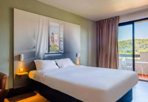 Un dormitorio con una cama grande con una ventana grande. en B&B HOTEL Villeneuve Loubet Village, en Villeneuve-Loubet