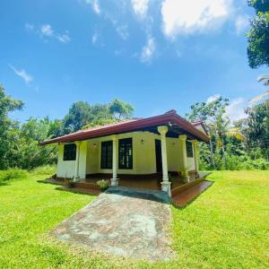 una pequeña casa amarilla con césped verde en Gama villa, en Ahangama