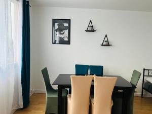 a dining room with a black table and green chairs at Bel appart house proche paris in Sarcelles