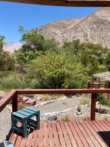 a green bench sitting on a wooden deck with a mountain at Cottages by the river in Rivadavia +41 photos