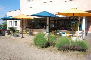 a patio with tables and umbrellas in front of a building at Gîte le pont de la Loire in Bourbon-Lancy