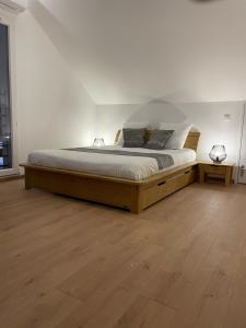 a large bed in a white room with wooden floors at les Gites de l’E.D.E. in Saint-Léger-les-Mélèzes