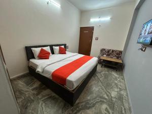 a bedroom with a bed with red pillows and a television at Hotel Ramya Palace in Gwalior +3 photos