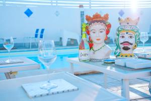 a table with two glasses of wine and statues on it at Residence Nonna Mariuccia in Mazara del Vallo