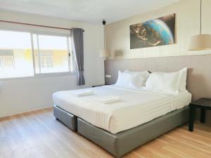 a bedroom with a large bed with white sheets at Whale Hostel Cha-Am in Cha Am