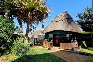 Cabaña pequeña con techo de hierba y palmera en The Leafy Haven, en Harare
