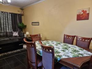 Una sala de estar con una mesa y sillas y un sofá. en The Leafy Haven, en Harare