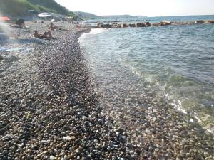 a rocky beach with a group of people on the water at Le Pietre Ricce B&B in Roccamontepiano