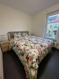 ein Schlafzimmer mit einem Bett mit einer geblümten Tagesdecke und einem Fenster in der Unterkunft Zeegidss in Ostende