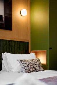 a bed with white pillows and a green wall at 6 VH Hotel in Paris
