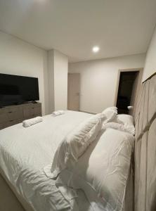 a bedroom with a large white bed and a flat screen tv at Apartamento Nuevo y Lujoso! in Mexico City +11 photos