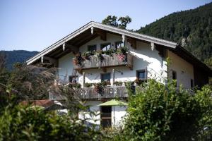 a white building with a balcony with flowers on it at Knogler-Bauer in Schleching