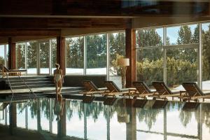 a woman standing in front of a pool with chairs at COMO Alpina Dolomites in Alpe di Siusi