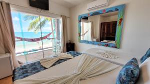 a bedroom with a bed with a mirror and a window at Pousada Casa da Sogra in Morro de São Paulo