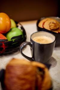 a cup of coffee next to a bowl of fruit at 6 VH Hotel in Paris