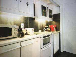 a kitchen with white cabinets and a microwave at Studio Croisette Palais des Festivals in Cannes