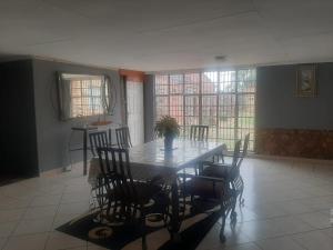 a dining room with a table and chairs and windows at Graceland Recreation in Bronkhorstspruit