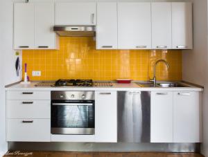 a kitchen with white cabinets and a sink at Hotiday Apartments Case Bianche in Orosei