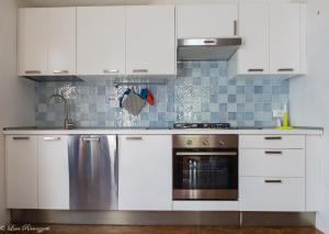 a kitchen with white cabinets and a stainless steel dishwasher at Hotiday Apartments Case Bianche in Orosei
