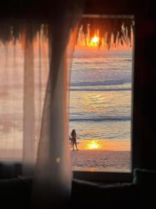 a person walking a dog on the beach at sunset at Buena Onda Surf House in León
