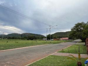 比勒陀利亚Kiewiets Creek Guesthouse的一条空的路,有田野和山地背景