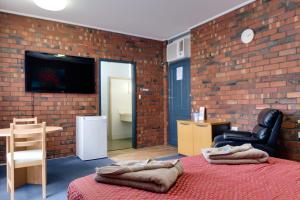 a bedroom with a brick wall with a bed and a television at Enfield Motel in Adelaide